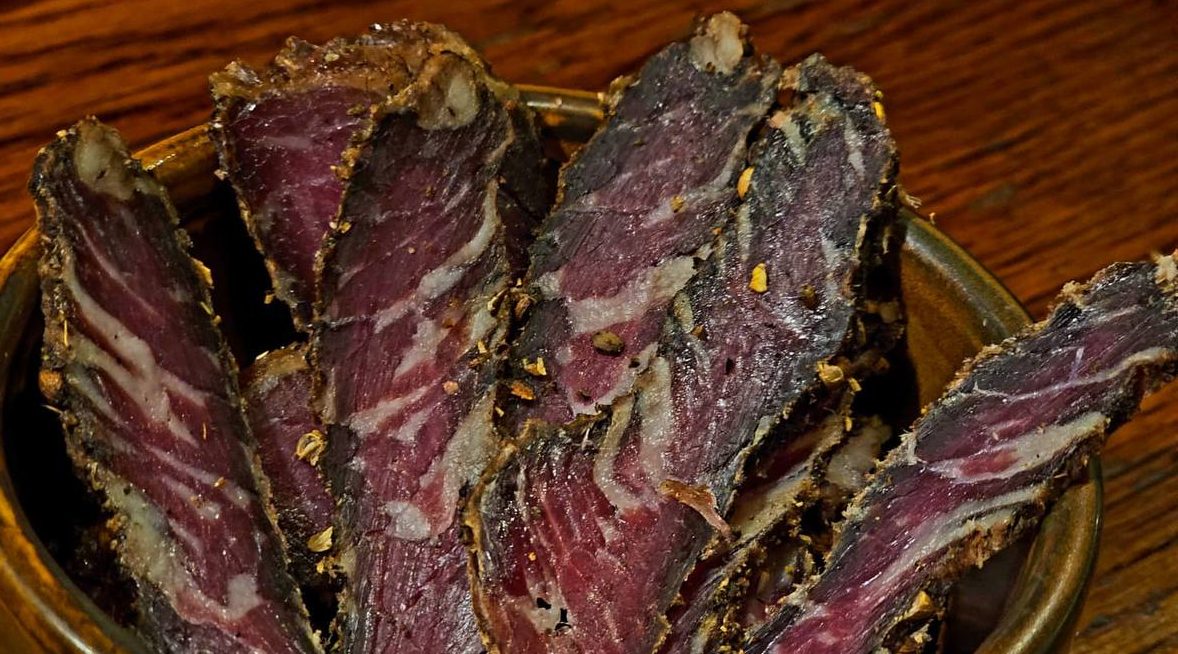 Slices of cured meat arranged in a wooden bowl.
